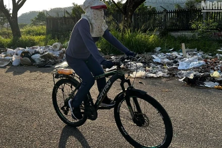 Người dân đi tập thể dục qua đoạn đường đầy rác thải, ảnh chụp chiều ngày 12/5. (Ảnh: ANH ĐÀO)