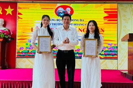 Phó Bí thư Thường trực Quận ủy Đống Đa Nguyễn Anh Cường trao quyết định kết nạp đảng viên cho hai học sinh ưu tú Trường THPT Hoàng Cầu.