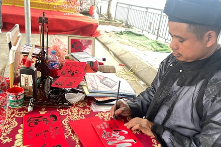 Anh Trần Hậu Thao viết chữ thư pháp tại khu di tích Đền Ông Hoàng Mười (Nghệ An).