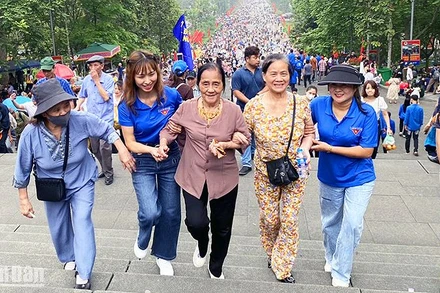 Tình nguyện viên hỗ trợ du khách cao tuổi trên đường lên Đền Hùng. 