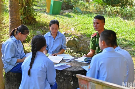 Đại úy Trần Đại Lượng ôn lại bài tập cùng học sinh trong khuôn viên trường.