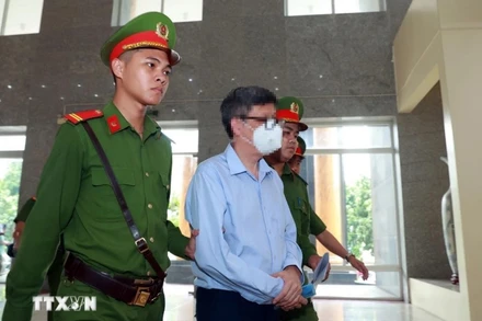 Lực lượng chức năng dẫn giải bị cáo Nguyễn Thanh Long (cựu Bộ trưởng Bộ Y tế) đến phiên tòa. (Ảnh: Phạm Kiên/TTXVN)