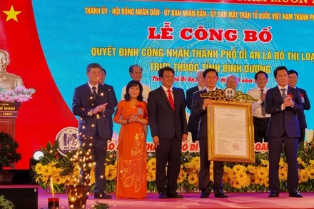 Thừa ủy nhiệm Thủ tướng Chính phủ, Thứ trưởng Xây dựng Nguyễn Tường Văn (phải) trao Quyết định công nhận thành phố Dĩ An là đô thị loại II cho lãnh đạo thành phố Dĩ An. 
