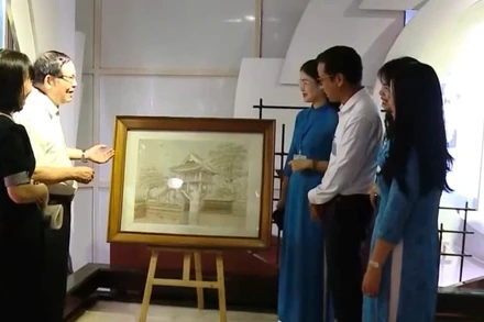 Ông Chu Đức Tính (người thứ 2 bên trái) giới thiệu về bức tranh thêu “Chùa Một Cột”.