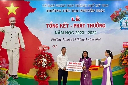Phó Giám đốc Sở Giáo dục và Đào tạo tỉnh Tiền Giang Huỳnh Thị Phượng nhận bảng tượng trưng 600 phụ san tranh panorama "Chiến dịch Điện Biên Phủ" của Báo Nhân Dân.