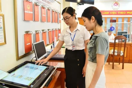 Cán bộ Ủy ban nhân dân phường Thanh Xuân Nam (quận Thanh Xuân, Hà Nội) hướng dẫn người dân thực hiện thủ tục hành chính trên môi trường mạng. (Ảnh: Thủy Nguyên/Báo Nhân Dân)