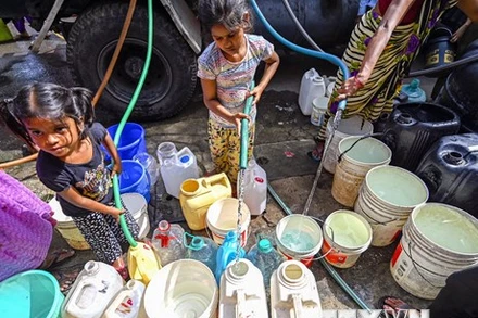 Các em nhỏ hứng nước sinh hoạt dưới trời nắng nóng tại New Delhi, Ấn Độ, ngày 22/5/2023. (Ảnh: AFP/TTXVN)