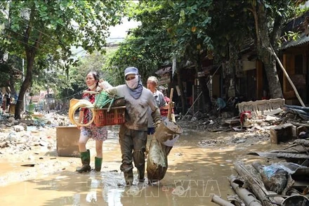Người dân lội bùn khi di chuyển trên 2 tuyến phố Thanh Niên và Trần Hưng Đạo (thành phố Yên Bái, tỉnh Yên Bái), chiều 14/9. (Ảnh: Tuấn Anh/TTXVN)