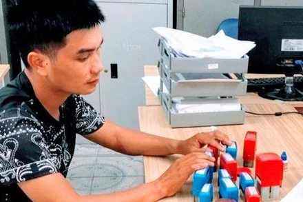 Đối tượng Phạm Đình Hậu cùng số con dấu giả bị thu giữ.