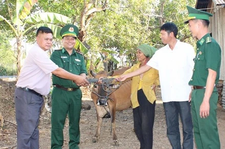 Thượng tá Rơ Lan Ngân, Phó Chính ủy Bộ đội Biên phòng tỉnh Đắk Lắk cùng đại diện các đơn vị trao tặng bò sinh sản cho bà H’Nhem Ê Ban tại xã biên giới Krông Na, huyện Buôn Đôn.