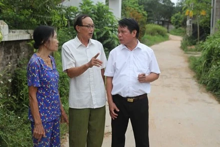 Ông Ma Hữu Khang (giữa) trao đổi về công tác vận động nhân dân hiến đất làm đường.