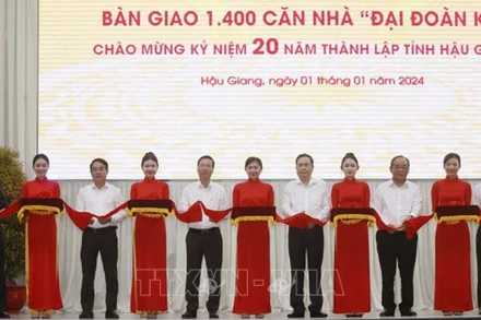 Chủ tịch nước Võ Văn Thưởng cùng các đại biểu thực hiện nghi thức bàn giao 1.400 căn nhà Đại đoàn kết tặng hộ nghèo Hậu Giang. (Ảnh: Thống Nhất/TTXVN)