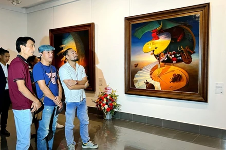 Hoạ sĩ Lê Thanh Bình (áo đỏ) giới thiệu tác phẩm của mình đến người xem tại triển lãm “Ký ức xuyên không” chiều 18/10. 