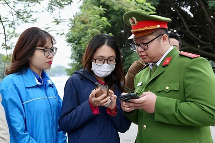 Cán bộ, chiến sĩ công an thành phố Hà Nội hướng dẫn người dân cài đặt VNelD, tư vấn phòng chống tội phạm trên không gian mạng. (Ảnh ĐĂNG CHUNG) 