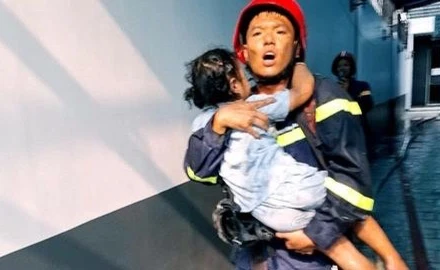 Lực lượng cứu hộ bế một em bé ra ngoài hiện trường vụ cháy.