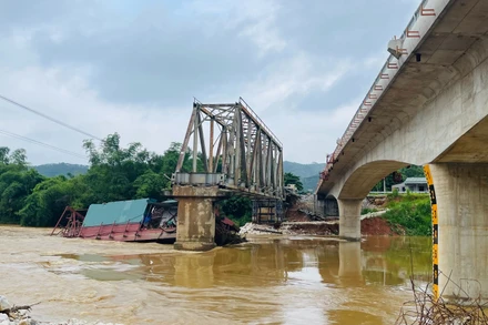 Chiếc tàu cuốc bị mắc kẹt vào trụ cầu Tô Mậu cũ đang trong quá trình tháo dỡ. (Ảnh: THANH SƠN)