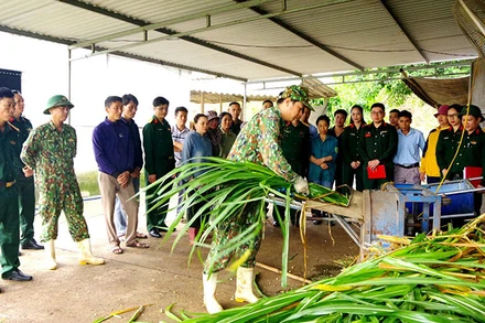 Cán bộ Căn cứ Hậu cần 1, Cục Hậu cần Quân khu 4 hướng dẫn người dân ở bản Mó, xã Nghĩa Xuân, huyện Quỳ Hợp (Nghệ An) cách chế biến thức ăn chăn nuôi bò.