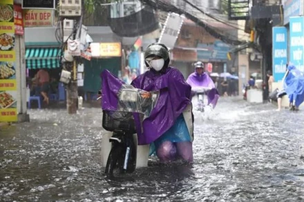 Người dân phải dắt bộ xe máy vì không thể di chuyển trong tình trạng ngập úng nặng. (Ảnh: PV/Vietnam+)
