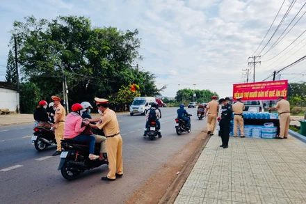 Lực lượng Cảnh sát giao thông Công an tỉnh Đồng Nai phát nước suối, khăn lạnh cho người dân về quê đón Tết trên quốc lộ 20.
