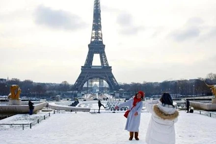 Khách du lịch chụp ảnh lưu niệm dưới chân tháp Eiffel. (Nguồn: TTXVN)