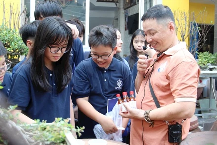 Anh Bùi Thanh Phú (ngoài cùng bên phải) giới thiệu với học sinh về nghề làm nước mắm.