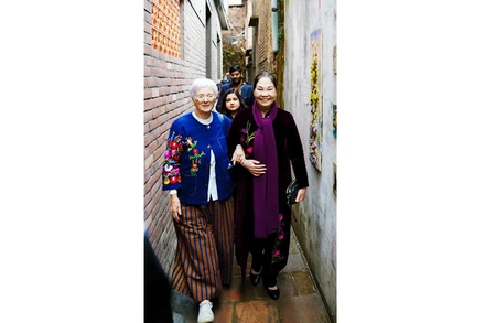 Nghệ nhân Hà Thị Vinh đón du khách nước ngoài thăm ngõ làng Bát Tràng.