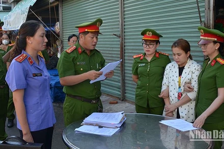 Cơ quan cảnh sát điều tra Công an thành phố Phan Thiết đọc Quyết định khởi tố bị can đối với Ngô Thị Loan Chi (áo trắng hoa), về tội “Lừa đảo chiếm đoạt tài sản”.