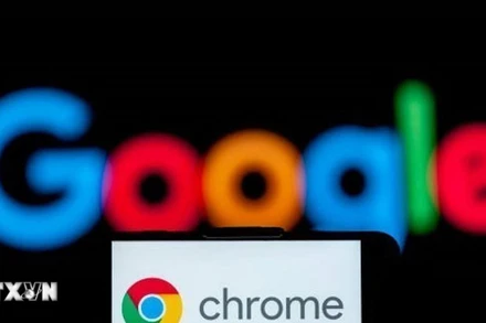 Biểu tượng Chrome trên màn hình điện thoại và biểu tượng Google (phía sau). (Ảnh: Getty Images/TTXVN)