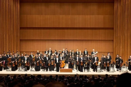 Nhạc trưởng Honna Tetsuji chỉ huy hai dàn nhạc hợp xướng. (Ảnh: TTXVN) 