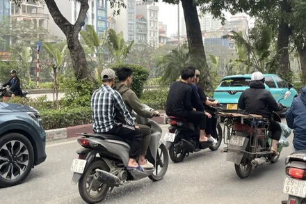 Xe máy "kẹp ba" và không đội mũ bảo hiểm - ghi nhận tại đường Láng, quận Đống Đa.