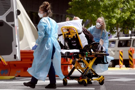 Nhân viên y tế chuyển bệnh nhân Covid-19 tới bệnh viện tại Melbourne, Australia. (Ảnh: AFP/TTXVN)