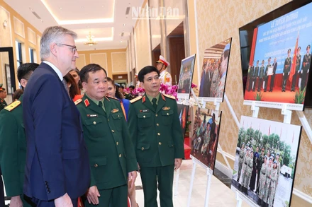 Thượng tướng Hoàng Xuân Chiến, Thứ trưởng Quốc phòng và Phó Tổng Thư ký Liên hợp quốc Jean-Pierre Lacroix cùng các đại biểu xem triển lãm ảnh về phụ nữ với hoạt động gìn giữ hòa bình Liên hợp quốc.