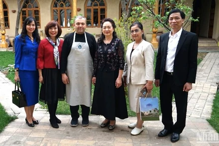 Phu nhân Chủ tịch Quốc hội và các thành viên tháp tùng chụp ảnh kỷ niệm với chủ gia đình cơ sở trưng bày gốm truyền thống Uzbekistan.