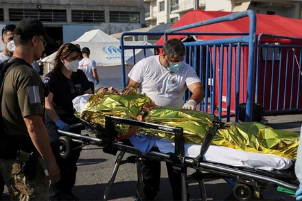 Nhân viên cứu nạn đưa người di cư lên xe cứu thương. (Ảnh: Reuters)