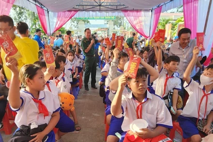 Học sinh biên giới tham dự chương trình chợ Tết yêu thương và nhận bao lì xì từ tay các bộ, chiến sĩ Đồn Biên phòng Sông Trăng, Long An trao. 