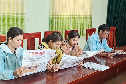 Đọc báo đầu ngày làm việc tại xã Rô Men, huyện Đam Rông, tỉnh Lâm Đồng. (Ảnh MAI VĂN BẢO) 