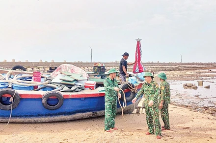 Cán bộ Đồn Biên phòng Bạch Long Vĩ (TP Hải Phòng) giúp ngư dân đưa tàu lên bờ tránh bão. (Ảnh VĂN TÁ)