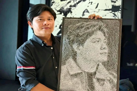 Nhạc sĩ Nguyễn Văn Chung bên bức tranh đinh chỉ nghệ thuật thể hiện chân dung mình. (Ảnh NVCC)