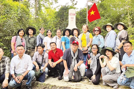 Du khách chụp ảnh bên cột mốc chủ quyền biên giới trong Vườn Quốc gia Lò Gò-Xa Mát.