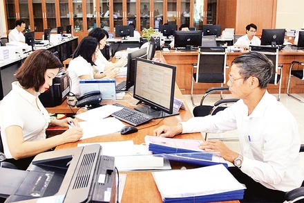 Cán bộ Trung tâm hành chính công tỉnh Thái Bình hỗ trợ người dân giải quyết thủ tục hành chính. (Ảnh THẾ DUYỆT) 