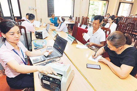 Người dân làm thủ tục vay vốn Ngân hàng Chính sách xã hội huyện Ba Vì tại điểm giao dịch xã Ba Trại. (Ảnh TRẦN VIỆT)