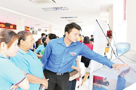 Đoàn viên, thanh niên hướng dẫn người dân thực hiện giao dịch hành chính qua nền tảng công nghệ tại UBND huyện Nhà Bè. (Ảnh THẾ ANH)