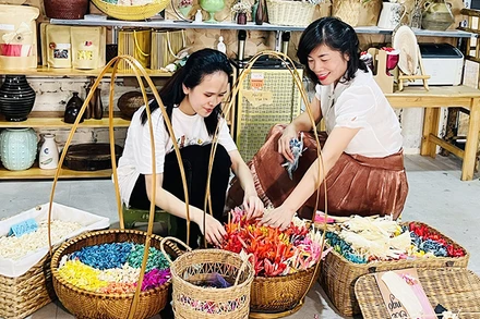 Chị Trang Phương (bên phải) đào tạo nghề cho bạn trẻ tại xưởng hoa khô Xavia (Hà Nội).
