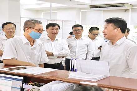 Tổng Giám đốc Bảo hiểm xã hội Việt Nam Nguyễn Thế Mạnh (ngoài cùng, bên phải) trao đổi với người dân đến làm việc tại Bảo hiểm xã hội Thành phố Hồ Chí Minh.