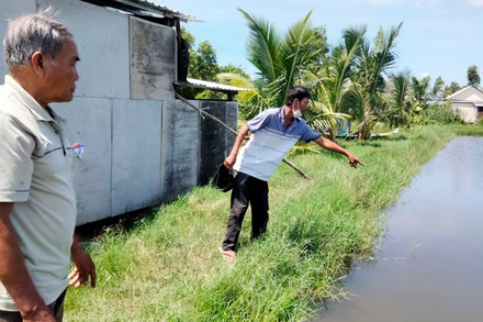 Ông Đặng Văn Đa (bên phải) chỉ nơi 2 cháu nội bị đuối nước tử vong.