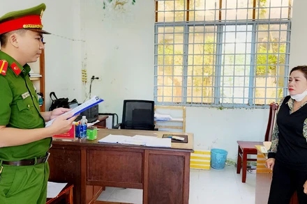 Cán bộ điều tra tống đạt quyết định khởi tố bị can đối với Võ Thị Thanh Nga. (Ảnh: VĂN VŨ)