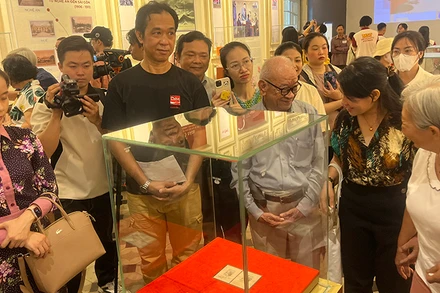 Khách tham quan thưởng lãm block tem kỷ niệm 70 năm Ngày sinh Chủ tịch Hồ Chí Minh có chữ ký của Người. (Ảnh: M.H)