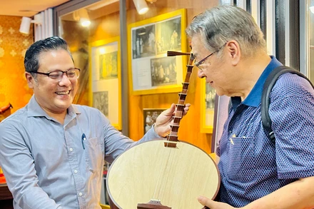 Nghệ sĩ Ưu tú Phan Quốc Kiệt (bìa trái), Giám đốc Nhà hát Cải lương Trần Hữu Trang tặng đoàn khách quốc tế cây đờn kìm. (Ảnh: Trung Sơn)