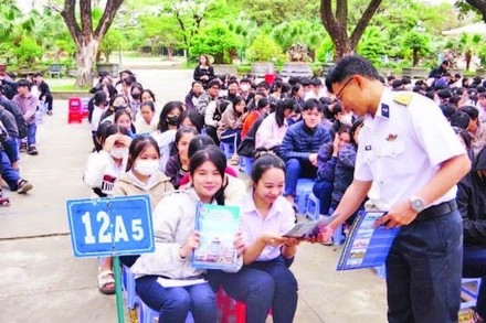 Báo cáo viên tuyên truyền, phát tờ rơi về thu hút nguồn nhân lực tại Trường THPT Hùng Vương, thành phố Quy Nhơn. (Ảnh THANH SANG)