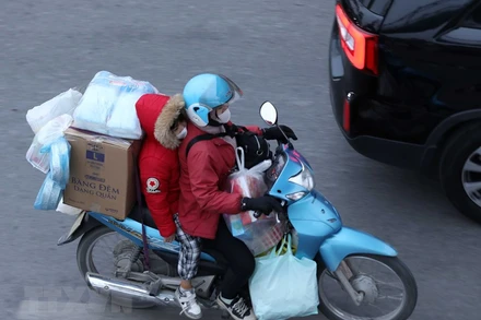 Dễ dàng bắt gặp chiếc xe máy chở cồng kềnh đồ đạc trên đường. (Ảnh: Hoàng Hiếu/TTXVN)